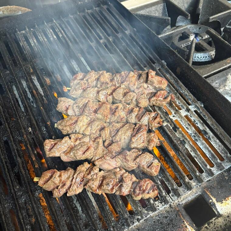 Meat cooking across the charcoal grill