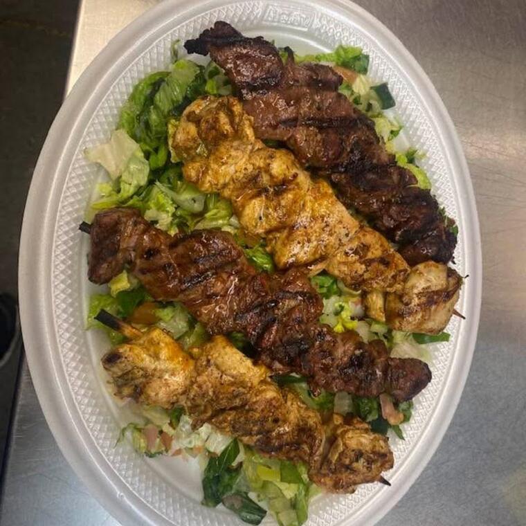 A platter of grilled meat over fresh salad